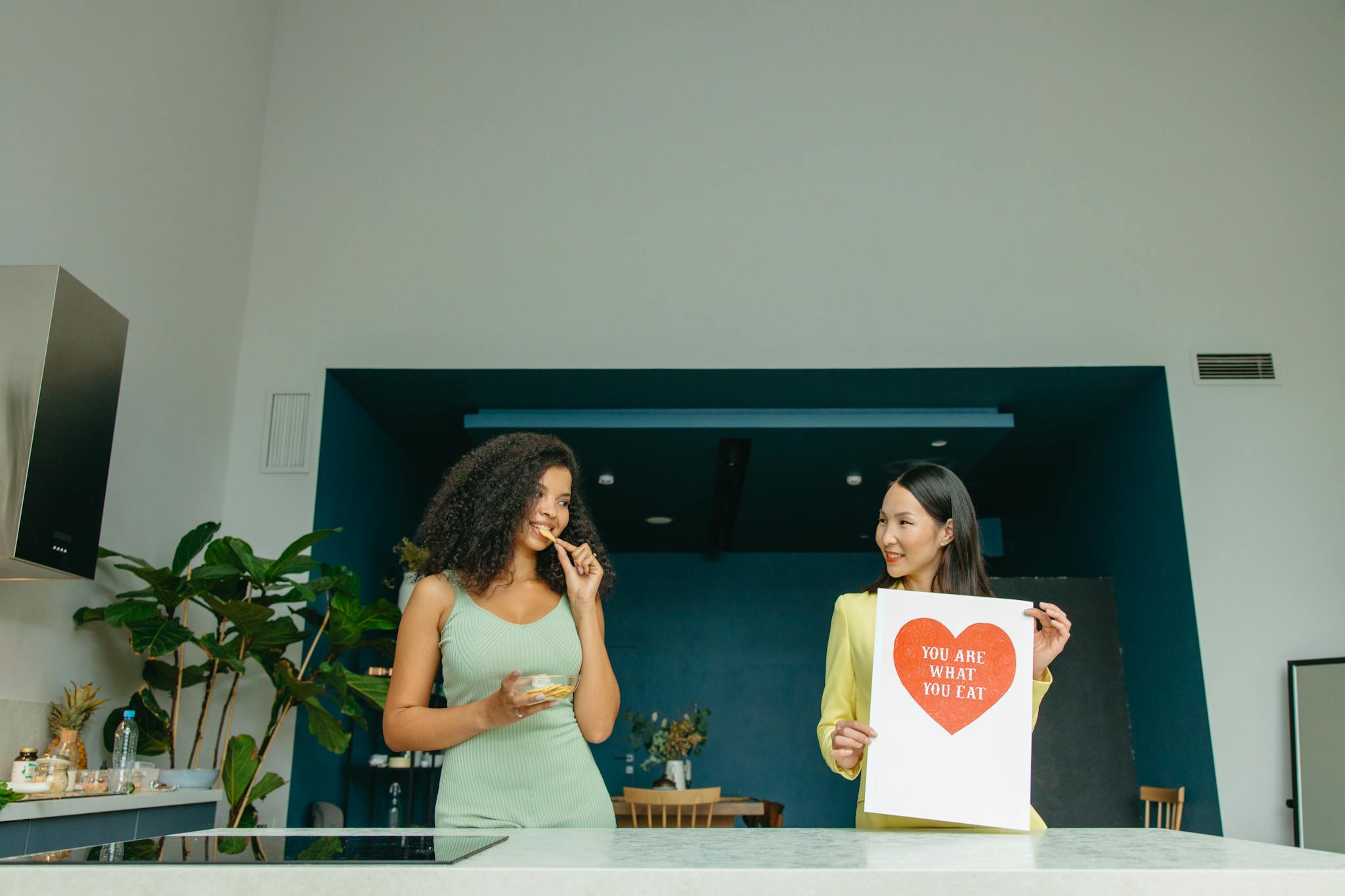 Two women enjoying healthy food and promoting nutrition awareness in a modern kitchen.